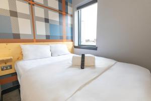 um quarto com uma cama branca com um livro em easyHotel Glasgow City em Glasgow