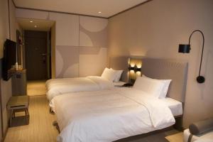 מיטה או מיטות בחדר ב-Hanting Hotel Fushun Wanda Plaza
