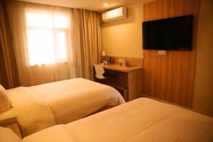 a hotel room with two beds and a desk and a television at Hanting Hotel Changzhi Town God Temple in Changzhi