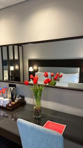 a vase of red flowers on a table in a bedroom at Ramada by Wyndham Downtown Beirut in Beirut