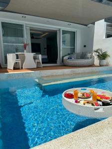 Una piscina con una mesa con una bandeja de comida. en Epic Suites Bohol ADULTS ONLY, en Dauis