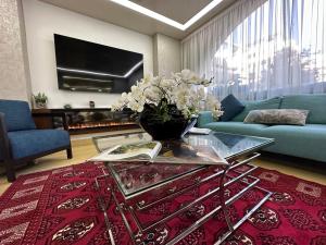 una sala de estar con un jarrón de flores sobre una mesa de cristal en Ramada by Wyndham Downtown Beirut en Beirut