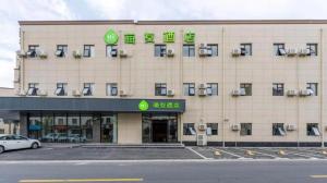 duży budynek z zielonymi znakami na przodzie w obiekcie Hi Inn Shanghai International Exhibition Center Jidi Road w Szanghaju