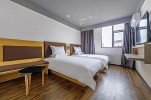 um quarto de hotel com duas camas e uma televisão em Hi Inn Shanghai International Exhibition Center Jidi Road em Xangai