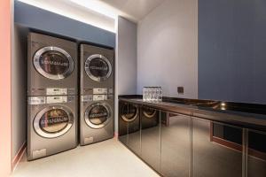 a laundry room with four washing machines and a counter at Hanting Hotel Nanjing Garden City Maihua Road in Yen-tzu-chi