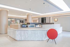 a lobby with a counter and a red chair at Ji Hotel Zibo Jinjing Avenue in Zibo