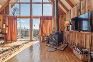 een woonkamer met een houtkachel en grote ramen bij Tranquil Rocky Top Cabin with Mountain Views! cabin in Slanesville