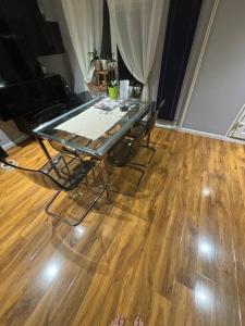 a glass table and chairs in a room with a wooden floor at 2 Bed Home in Luton