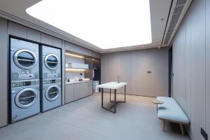 a laundry room with three washing machines and a table at Ji Hotel Dandong Railway Station in Dandong