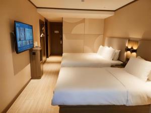 Cette chambre comprend 2 lits et une télévision à écran plat. dans l'établissement Hanting Hotel Qingdao Nanjing Road, à Fushansuo