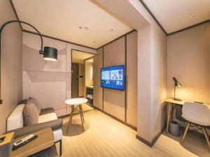 - un salon avec un canapé et une télévision murale dans l'établissement Hanting Hotel Qingdao Nanjing Road, à Fushansuo