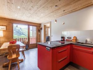 a kitchen with red cabinets and a dining room with a table at Appartement La Clusaz, 6 pièces, 7 personnes - FR-1-304-175 in La Clusaz