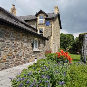 una casa de piedra con flores delante en Bronwye en Builth Wells