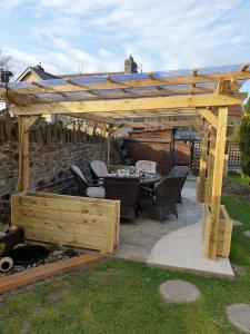 pérgola de madera con mesa y sillas debajo en Bronwye, en Builth Wells