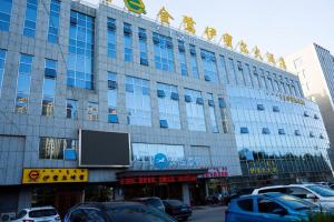 un grande edificio con macchine parcheggiate di fronte di Hanting Hotel Ordos Yijinholoqi Wenming Road a Ordos