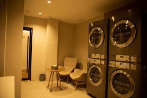 a laundry room with three washing machines and a table at Hanting Hotel Ordos Yijinholoqi Wenming Road in Ordos