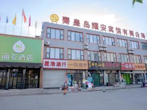 ein großes Gebäude mit Schildern darüber in der Unterkunft Hi Inn Qinhuangdao Railway Station in Qianmafang