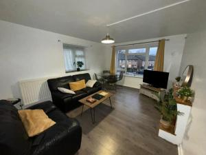 sala de estar con sofá negro y mesa en Toni's Hub - 2 bed City Centre Apartment en Derby