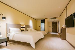 Habitación de hotel con 2 camas y TV de pantalla plana. en Hanting Hotel Yan'An Railway Station en Yan'an