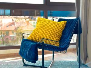 a blue chair with a yellow pillow in front of a window at 4 Bdr 2 Bth Netflix Panorama Views in Sofia