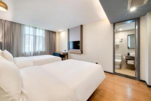 a hotel room with a white bed and a bathroom at Hanting Hotel Hangzhou Zhejiang University City College in Hangzhou