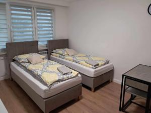 2 camas en una habitación con mesa y ventana en Apartament Julia 1-4 os parter Centrum, en Kielce