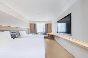 a hotel room with two beds and a flat screen tv at Ji Hotel Wuhan Yellow Crane Tower Shouyi Road in Han-yang-hsien