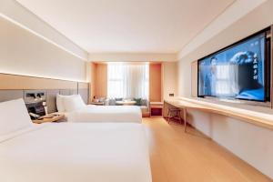 ein Hotelzimmer mit 2 Betten und einem Flachbild-TV in der Unterkunft Ji Hotel Bayanzhuo'Er Books Tower in Bayan Nur