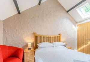 a bedroom with a bed and a red chair at Stable Cottage in Pembroke