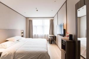 a bedroom with a large white bed and a mirror at Hanting Hotel Shanghai Qingpu Huijin Road Metro Station in Qingpu