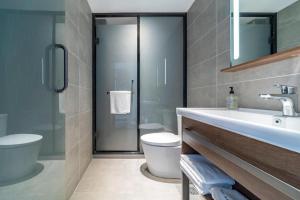 a bathroom with a sink and a toilet and a mirror at Hanting Hotel Shanghai Safari Park Nanzhu Road in Ssu-t'uan-ts'ang