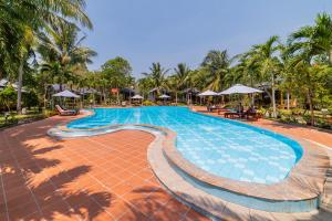 a swimming pool at a resort with palm trees at Dugong Resort Phu Quoc in Phu Quoc