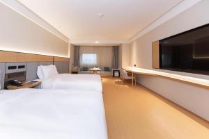 a hotel room with two beds and a flat screen tv at Ji Hotel Nanjing Xianlin Wandamao in Dongchanglin