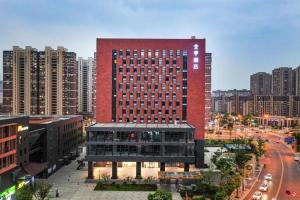 a tall red building in the middle of a city at Ji Hotel Nanjing Xianlin Wandamao in Dongchanglin