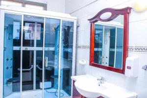 La salle de bains est pourvue d'une douche en verre et d'un lavabo. dans l'établissement Lidia's Place Guest House, à Maputo