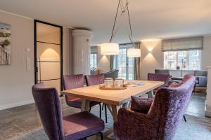 a dining room with a wooden table and purple chairs at Reethus Westerheide in Nieblum