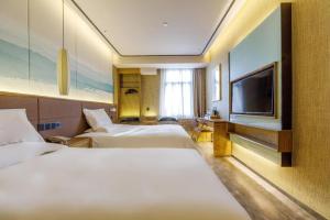 a hotel room with two beds and a flat screen tv at Hanting Premium Hotel Shanghai Stadium Metro Station in Shanghai