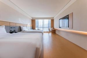 a hotel room with two beds and a flat screen tv at Ji Hotel Jinzhou Red Star Macalline in Jinzhou