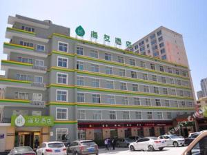 un grand bâtiment avec des voitures garées dans un parking dans l'établissement Hi Inn Xining Mojia Street, à Xining