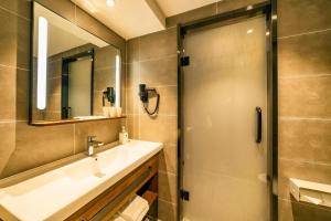 een badkamer met een douche, een wastafel en een spiegel bij Hanting Hotel Qingdao Xianggang Zhong Road Aofan Center in Qingdao