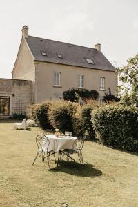 諾南特的住宿－LE CLOS POULAIN Petits gîtes de charme et chambres d'hôtes Familiales au calme proche Bayeux et des plages，房子前面的一张桌子和椅子