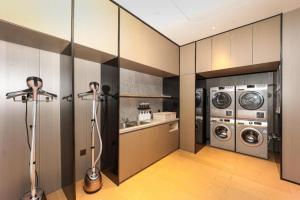 a laundry room with three washing machines and a washer and dryer at Ji Hotel Shanghai Xujiahui Guanshengyuan Road in Shanghai