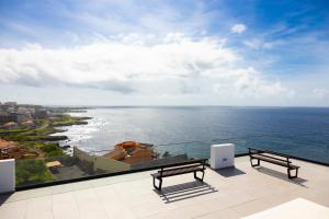 a balcony with two benches and a view of the ocean at Lux 3-BR: Panoramic Sea View & Rooftop Pool in Praia