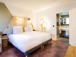 sypialnia z dużym białym łóżkiem i łazienką w obiekcie Mercure Cannes Mandelieu w Cannes