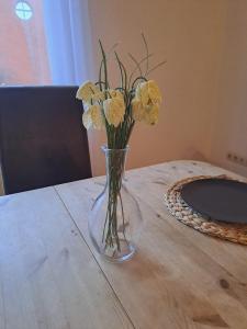 um vaso de vidro com flores amarelas sobre uma mesa em Zentrale 3-Zimmer-Ferienwohnung em Ilmenau