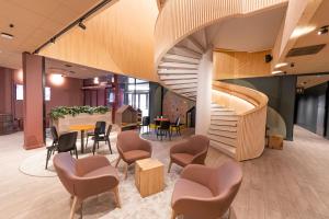 - un escalier en colimaçon dans le hall avec des chaises et des tables dans l'établissement Break Sokos Hotel Koli Kylä, à Kolinkylä