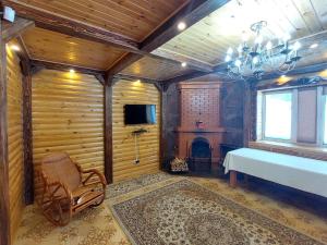 Barmashino的住宿－Krona Borovoe，一间卧室配有一张床、一台电视和一个壁炉