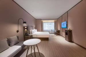 een hotelkamer met een bed en een bank bij Hanting Hotel Taizhou Jiangyan Pedestrian Street in Guanzhuang