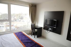 Pokój z łóżkiem, telewizorem i oknem w obiekcie Balaji gold inn hotel w mieście Hubballi-Dharwar