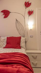 sypialnia z czerwonym łóżkiem i malowidłem kwiatowym na ścianie w obiekcie Suite Modena al Centro - Affitti Brevi Italia w mieście Modena
